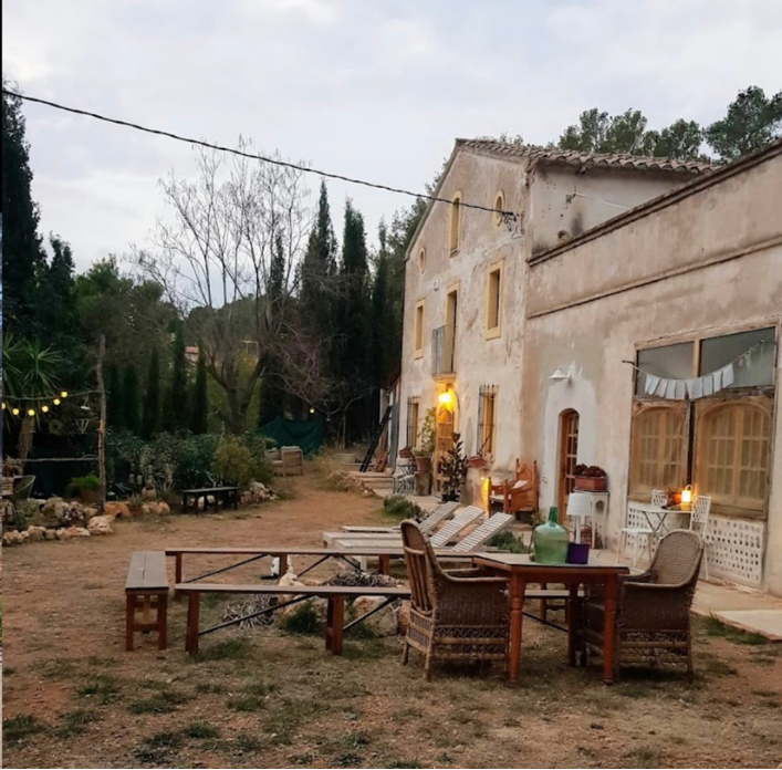 Exterior de una masía con mesas en el jardín